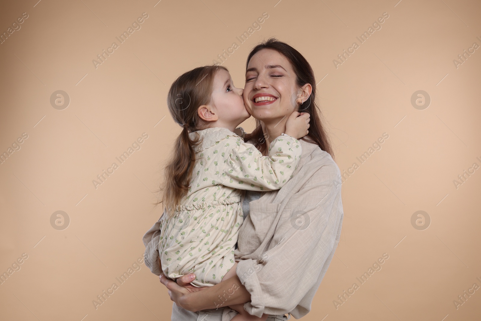 Photo of Happy mother with her cute little daughter on beige background