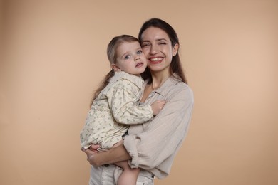 Photo of Portrait of happy mother with her cute little daughter on beige background