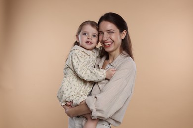 Photo of Portrait of happy mother with her cute little daughter on beige background