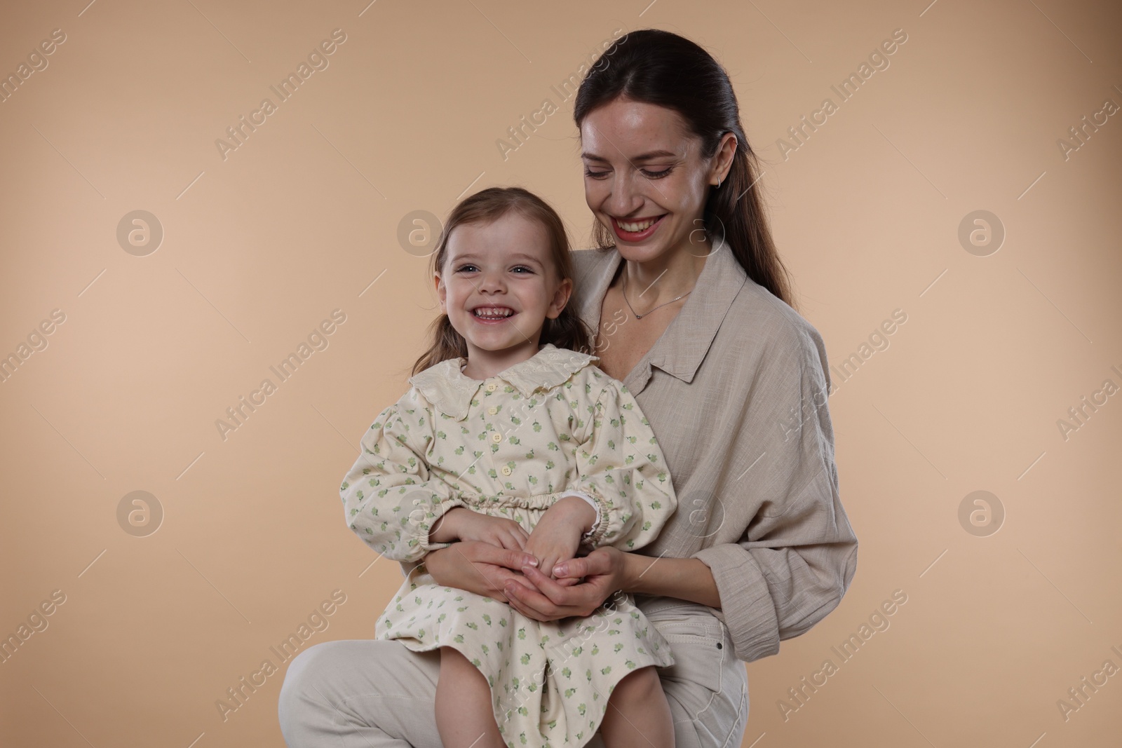 Photo of Happy mother with her cute little daughter on beige background