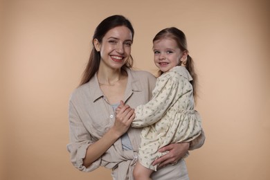 Photo of Portrait of happy mother with her cute little daughter on beige background