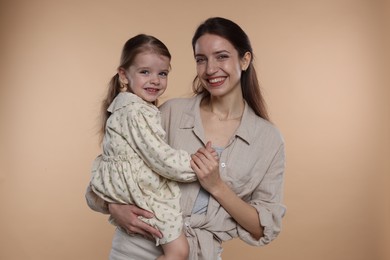 Photo of Portrait of happy mother with her cute little daughter on beige background