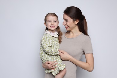 Photo of Happy mother with her cute little daughter on grey background