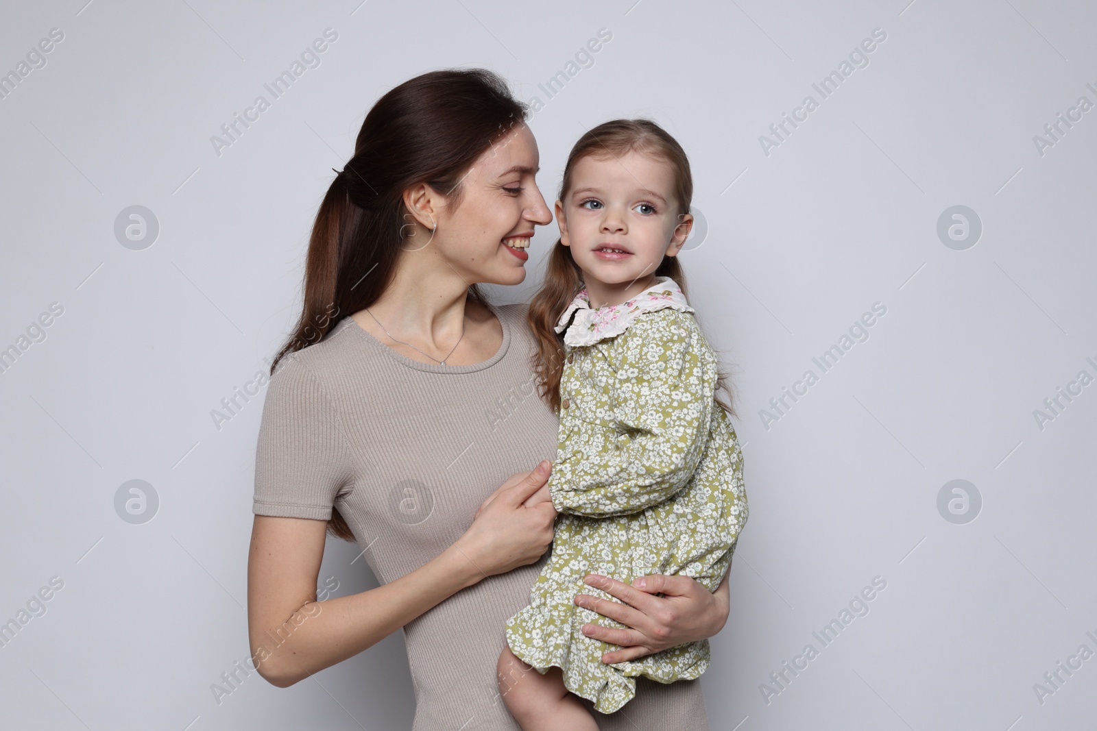 Photo of Happy mother with her cute little daughter on grey background