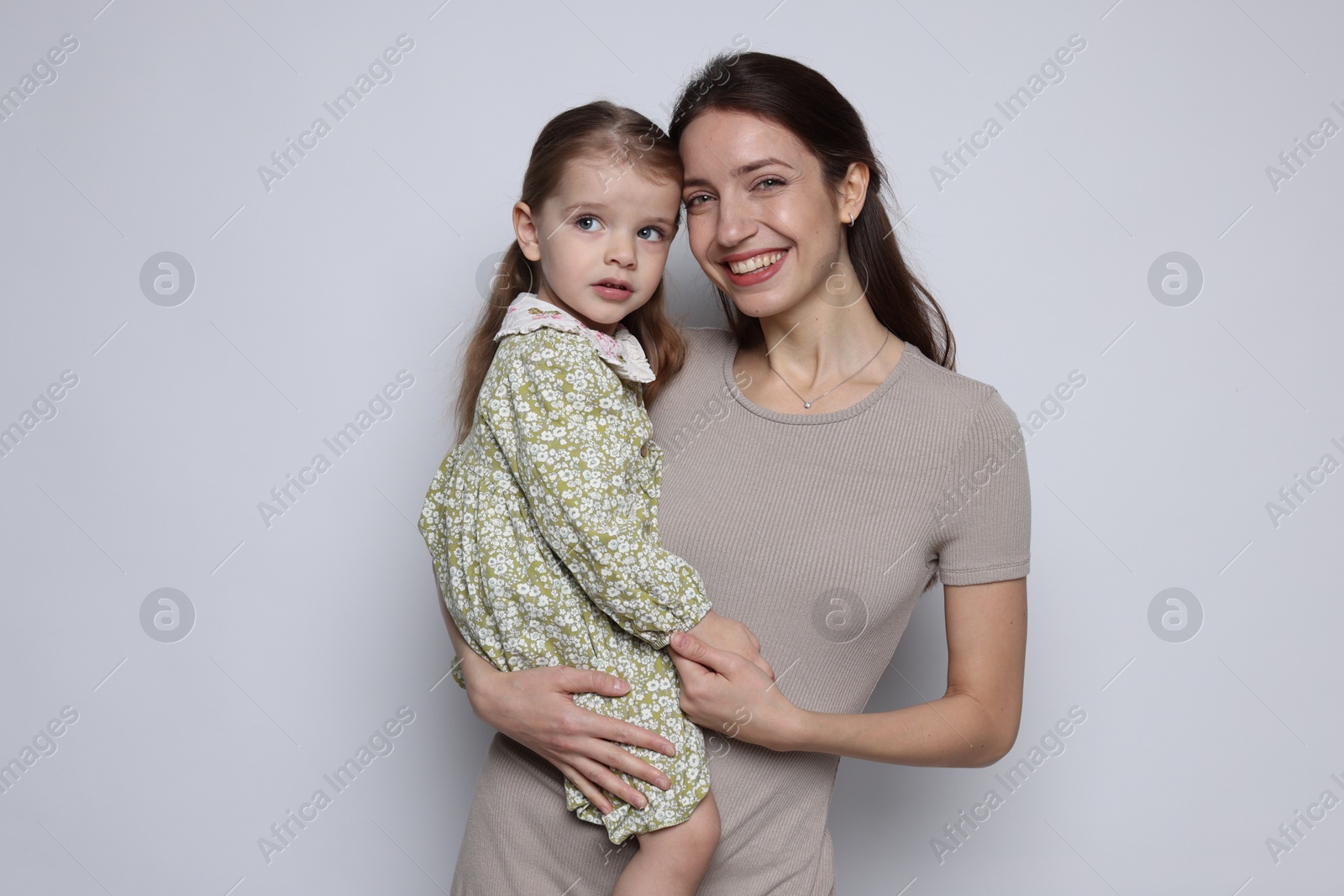 Photo of Portrait of happy mother with her cute little daughter on grey background