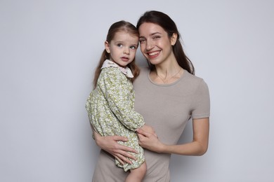 Photo of Portrait of happy mother with her cute little daughter on grey background