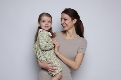 Photo of Happy mother with her cute little daughter on grey background