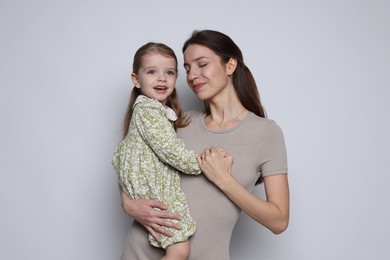 Photo of Beautiful mother with her cute little daughter on grey background