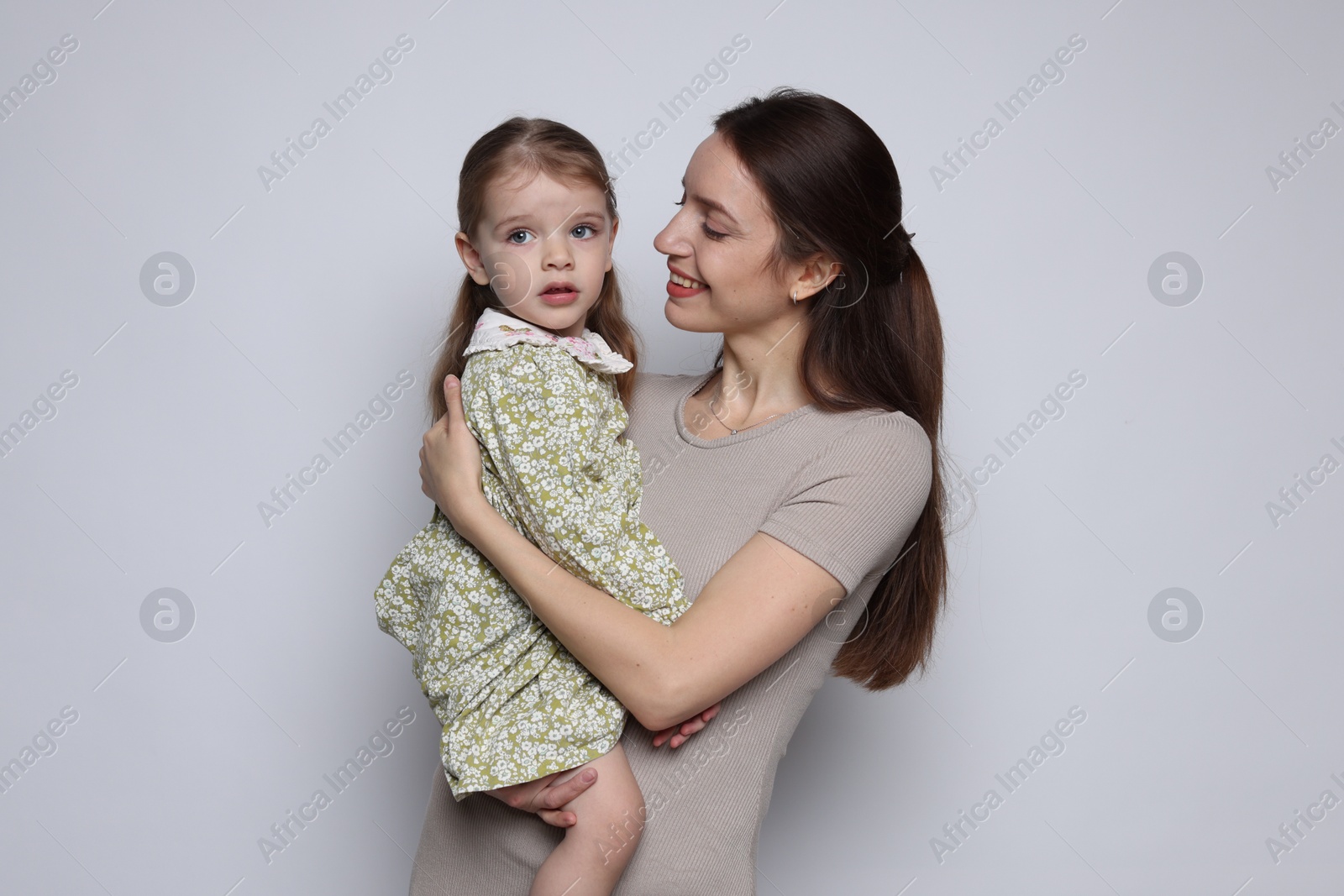 Photo of Happy mother with her cute little daughter on grey background