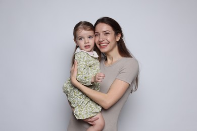 Photo of Portrait of happy mother with her cute little daughter on grey background