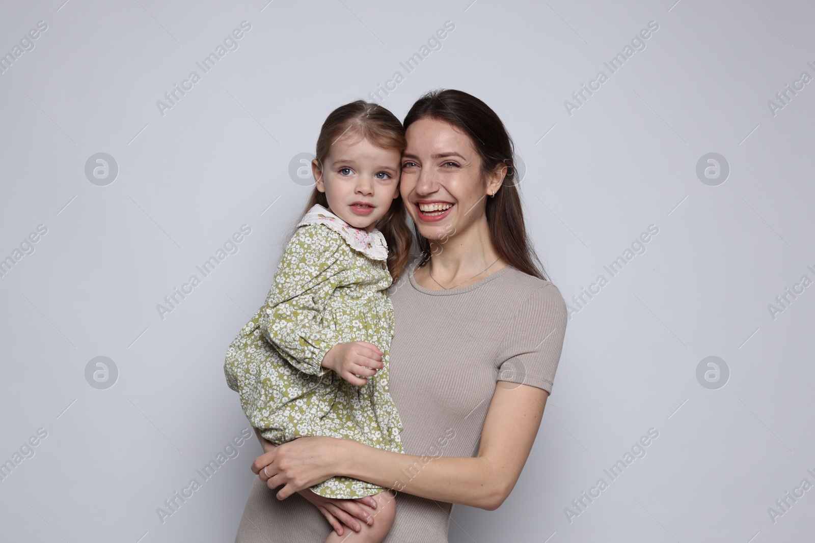 Photo of Portrait of happy mother with her cute little daughter on grey background