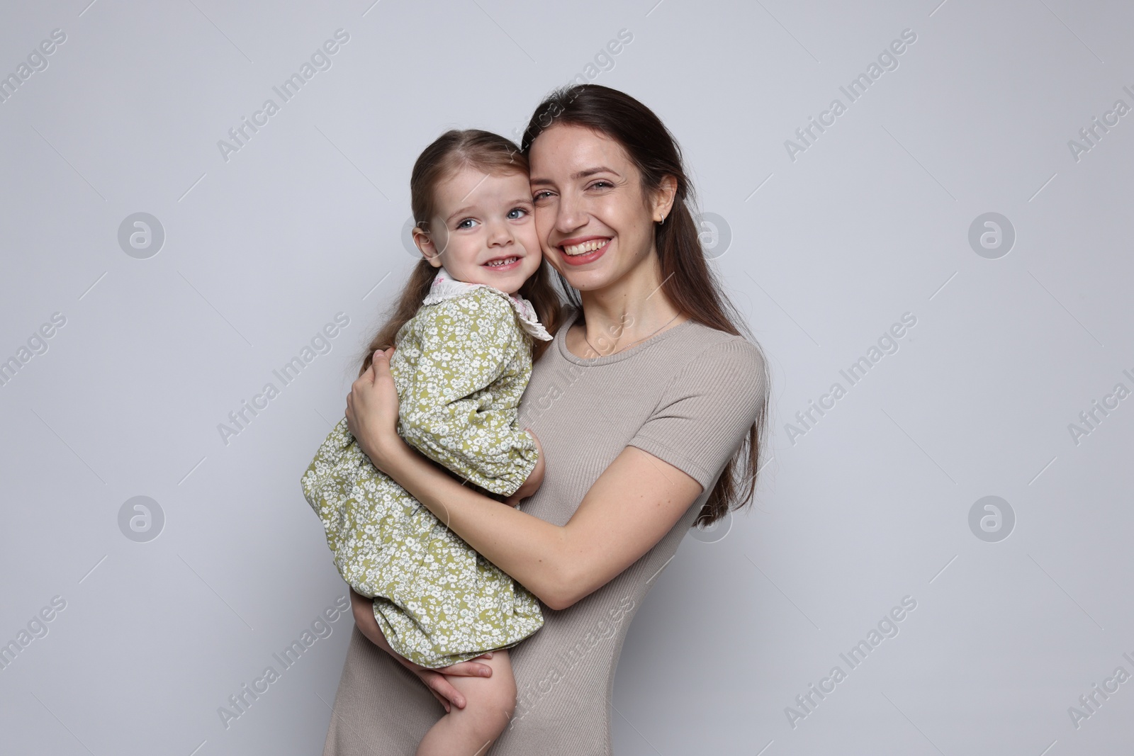 Photo of Portrait of happy mother with her cute little daughter on grey background