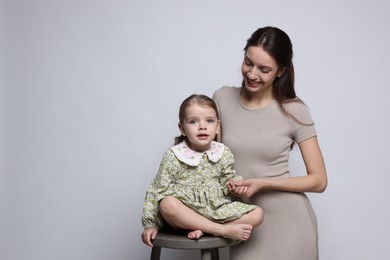 Photo of Happy mother with her cute little daughter on grey background, space for text