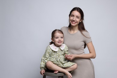 Photo of Portrait of happy mother with her cute little daughter on grey background, space for text