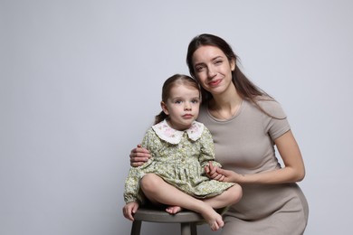 Photo of Beautiful mother with her cute little daughter on grey background, space for text