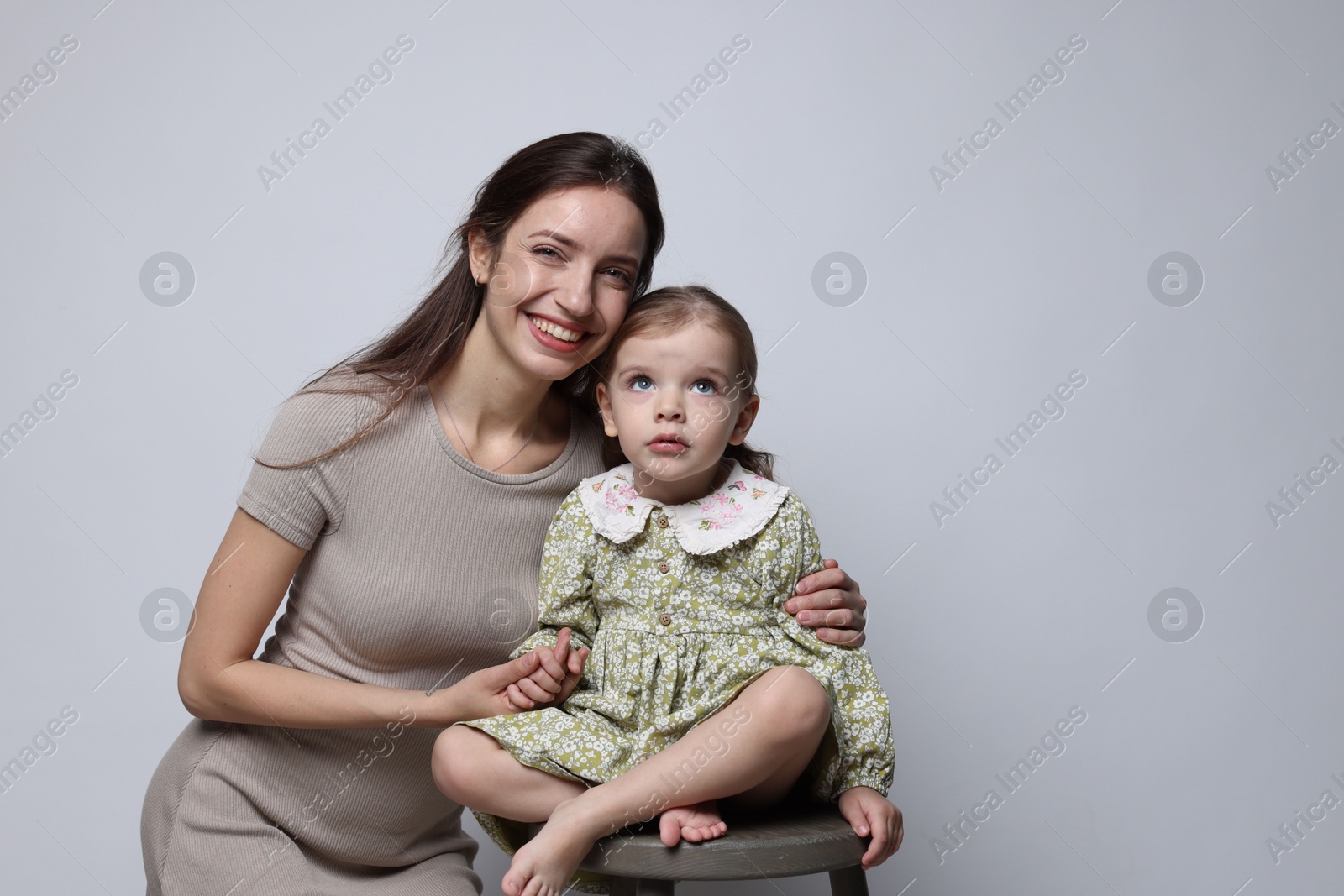 Photo of Portrait of happy mother with her cute little daughter on grey background, space for text