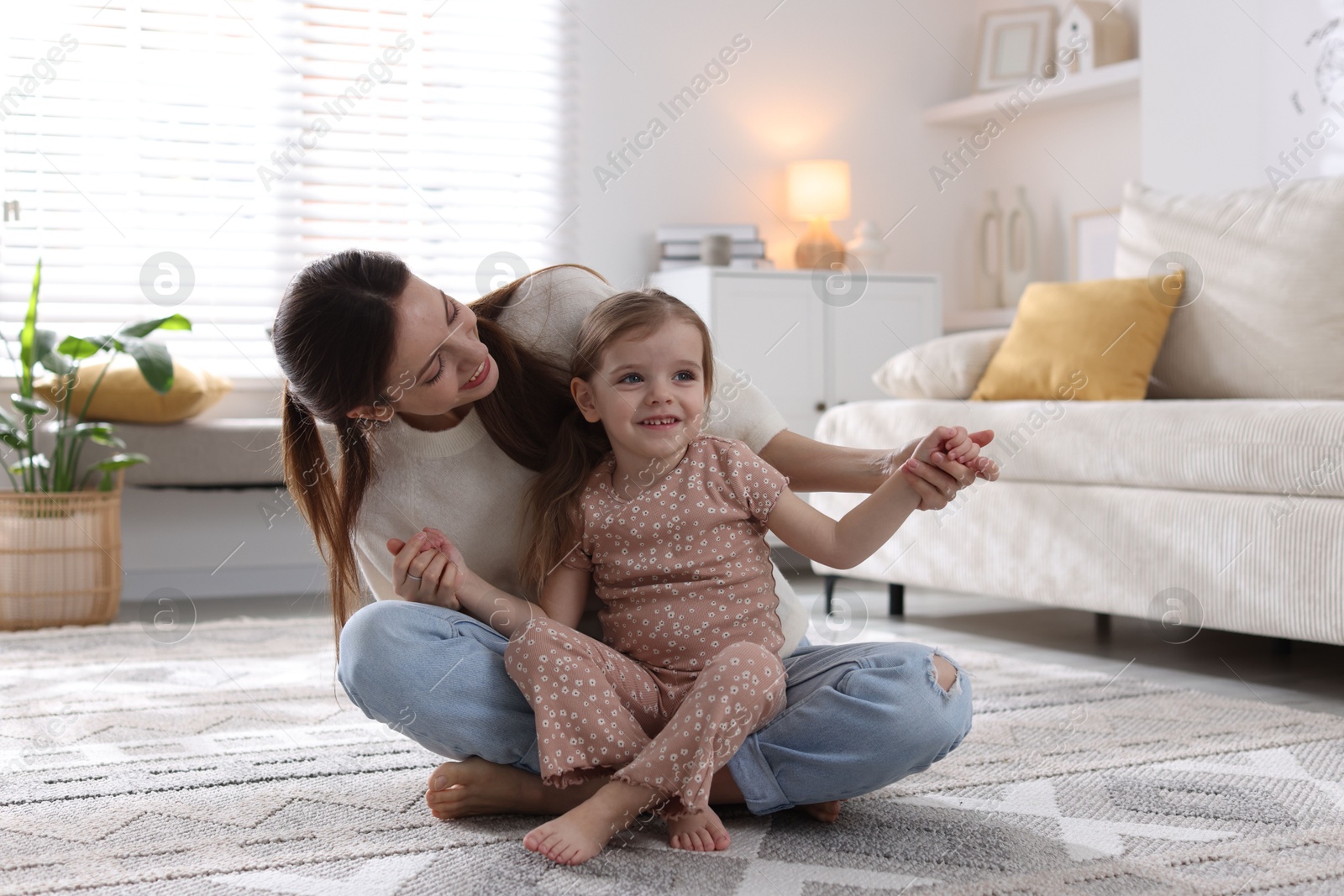 Photo of Happy mother with her cute little daughter on carpet at home