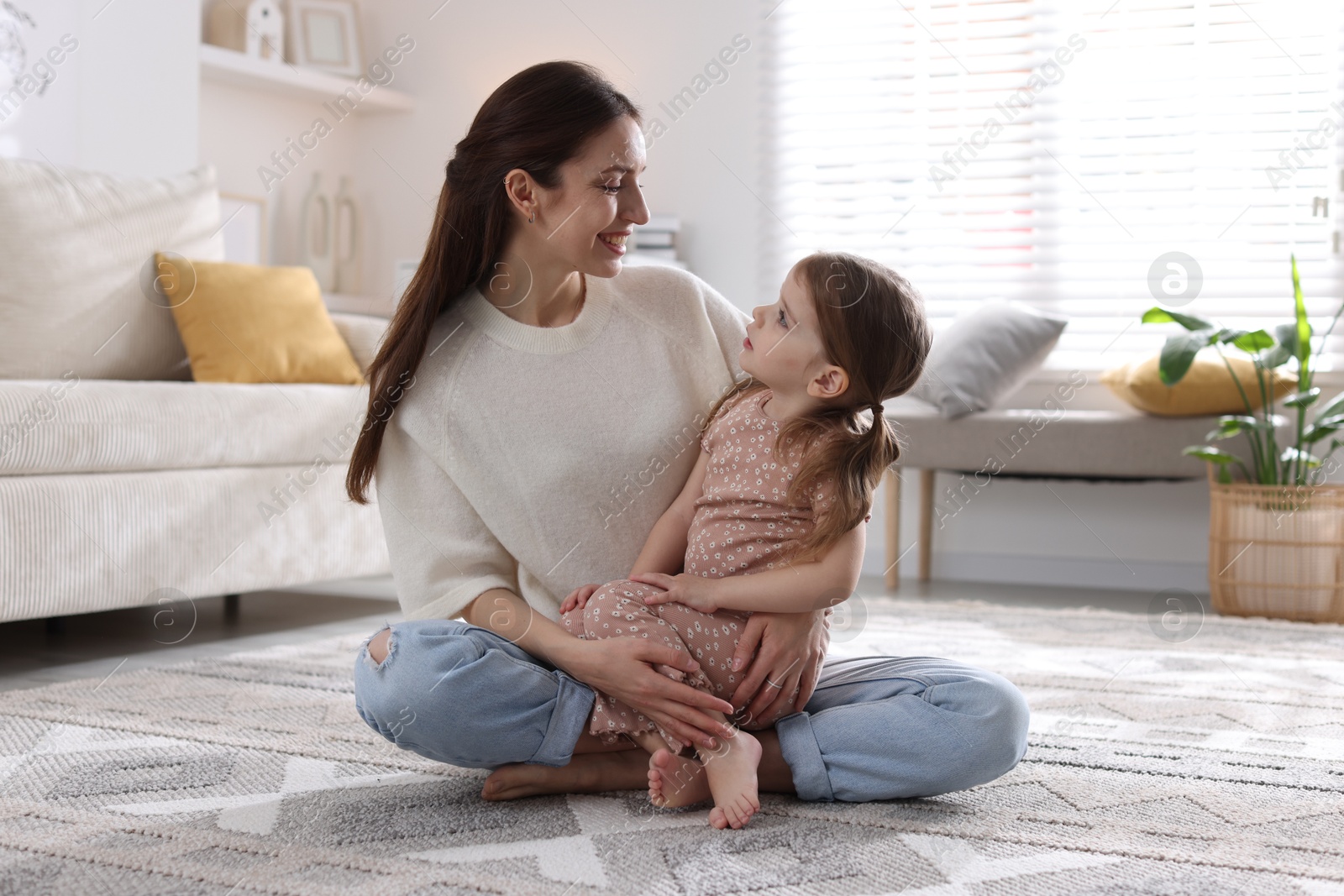 Photo of Happy mother with her cute little daughter on carpet at home