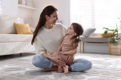 Photo of Happy mother with her cute little daughter on carpet at home