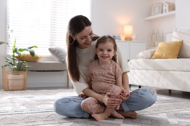 Photo of Happy mother with her cute little daughter on carpet at home