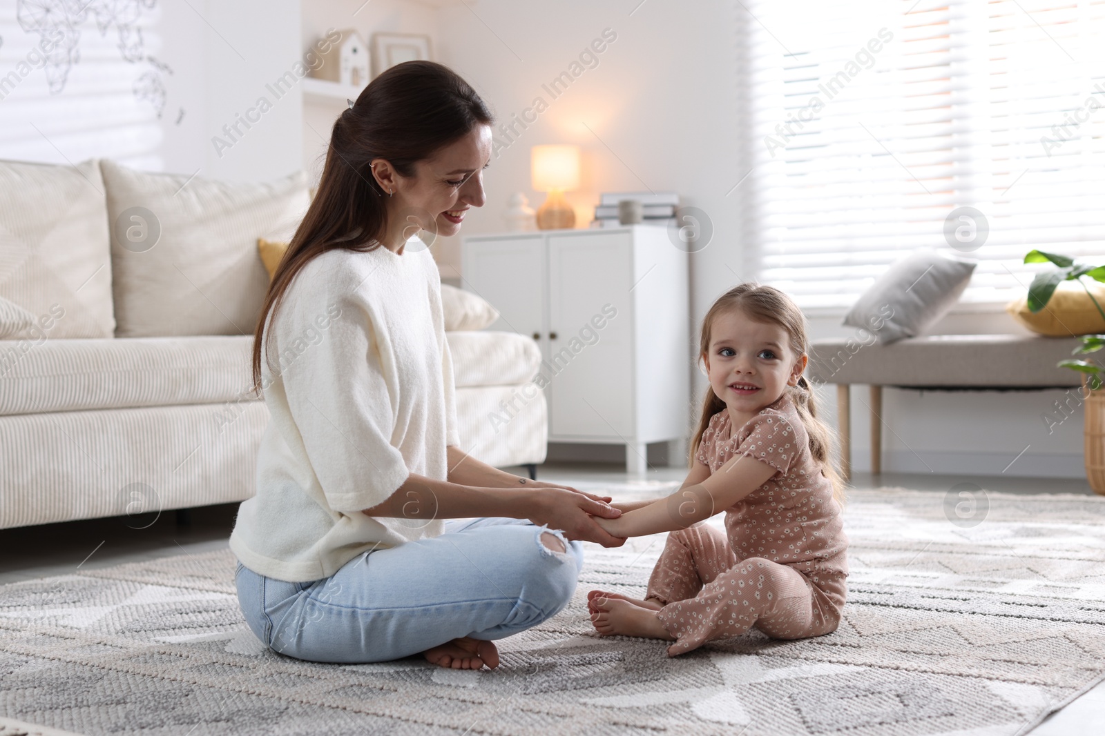 Photo of Happy mother with her cute little daughter on carpet at home