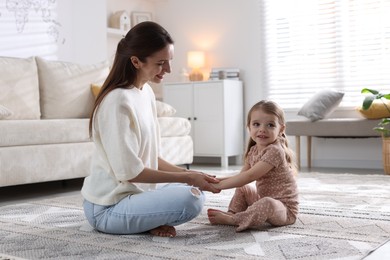 Photo of Happy mother with her cute little daughter on carpet at home