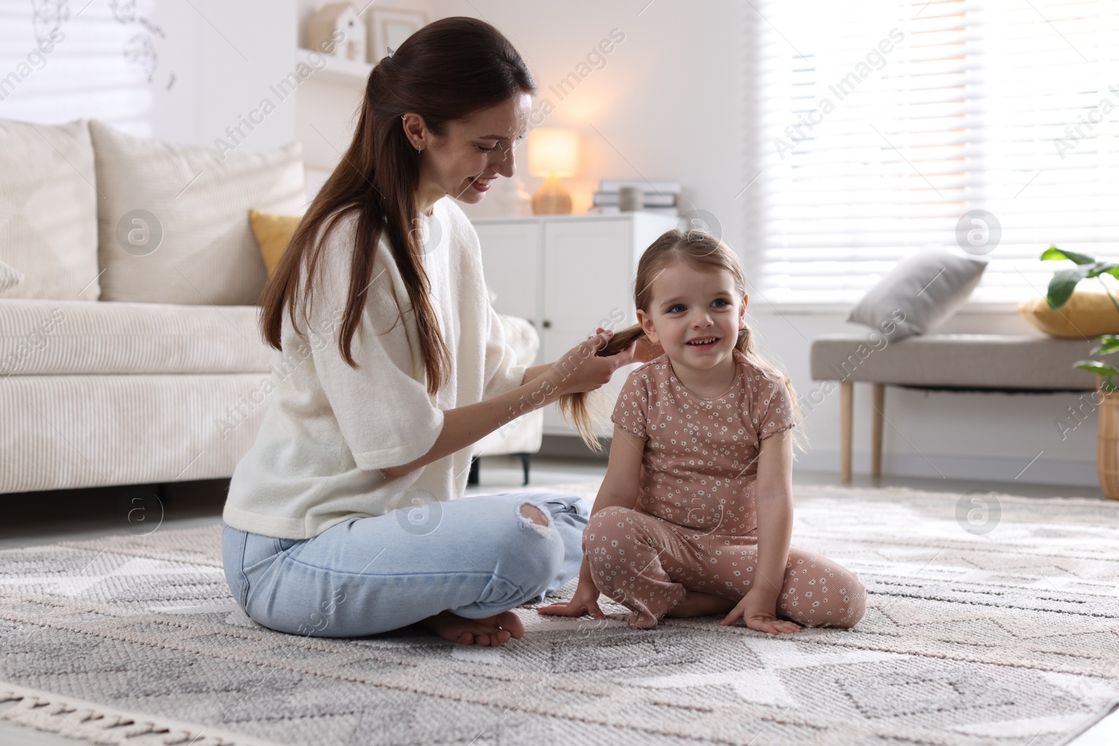 Photo of Happy mother with her cute little daughter on carpet at home