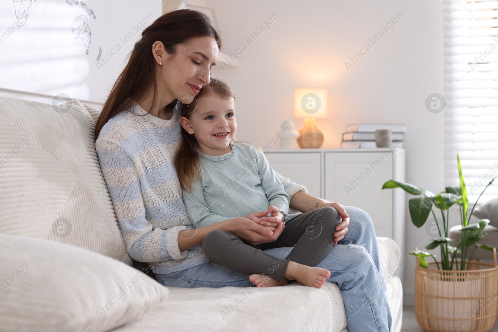 Photo of Beautiful mother with her cute little daughter on sofa at home