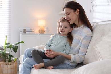 Photo of Beautiful mother with her cute little daughter on sofa at home