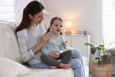 Photo of Happy mother with her cute little daughter on sofa at home