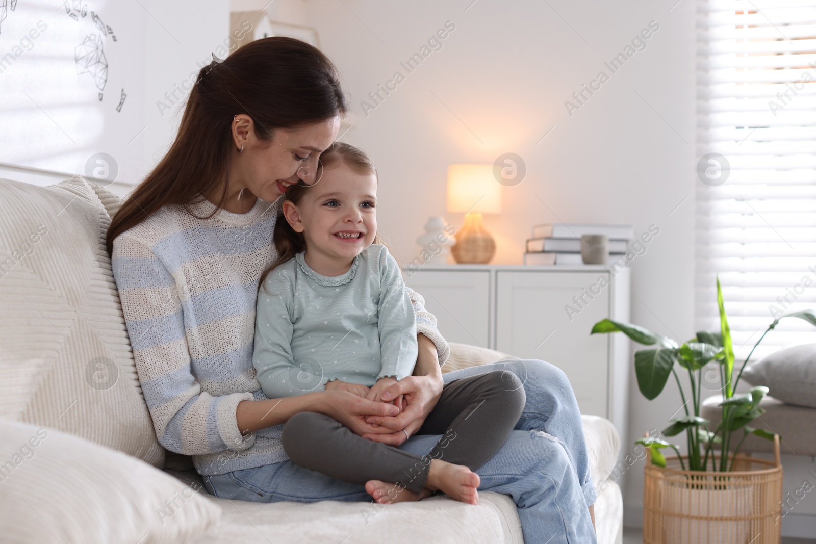 Photo of Happy mother with her cute little daughter on sofa at home