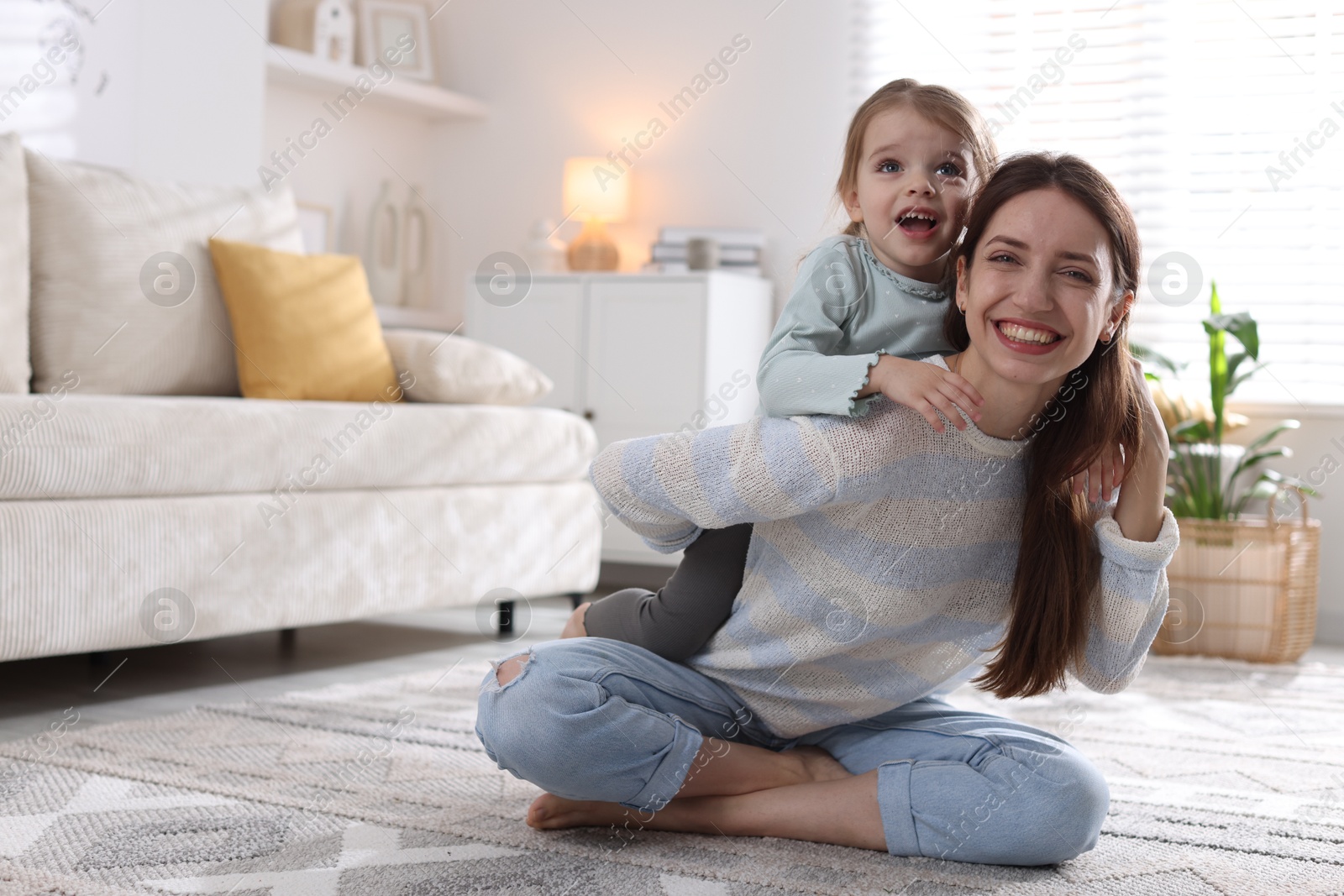 Photo of Happy mother with her cute little daughter on carpet at home