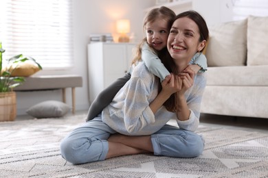 Photo of Happy mother with her cute little daughter on carpet at home