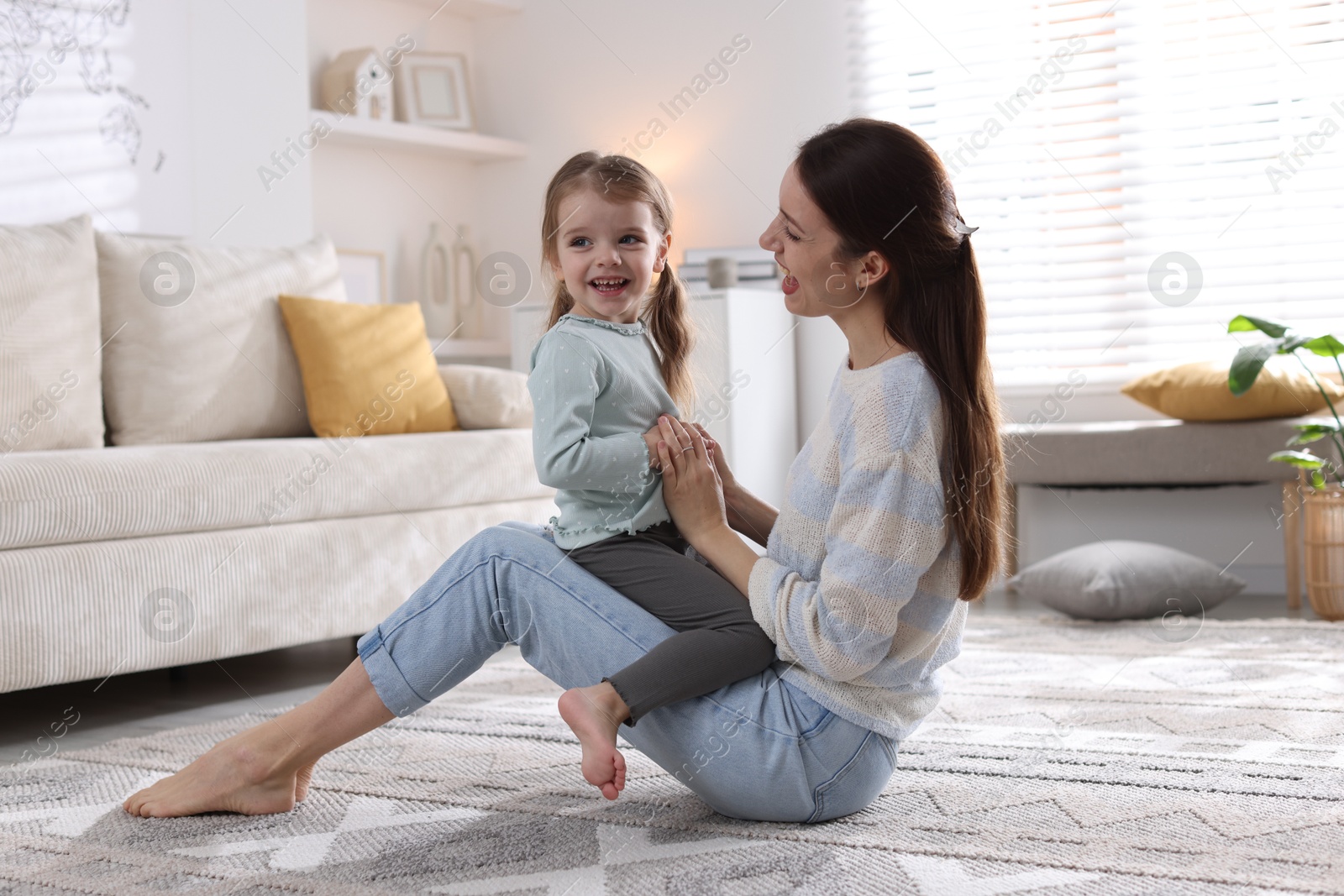 Photo of Happy mother with her cute little daughter on carpet at home