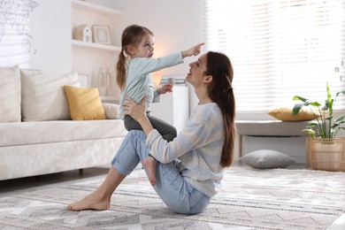 Photo of Happy mother with her cute little daughter on carpet at home