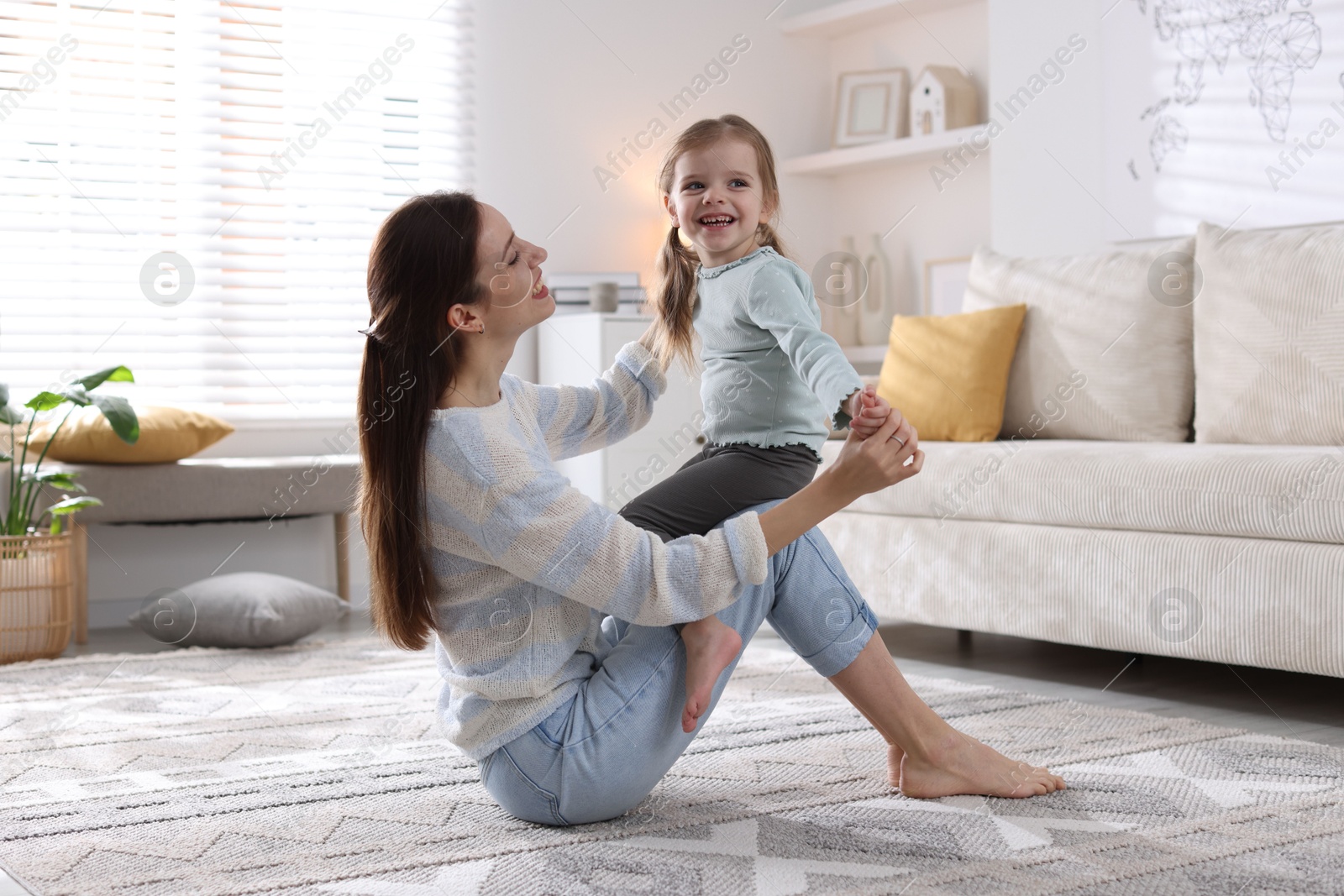 Photo of Happy mother with her cute little daughter on carpet at home