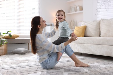 Photo of Happy mother with her cute little daughter on carpet at home