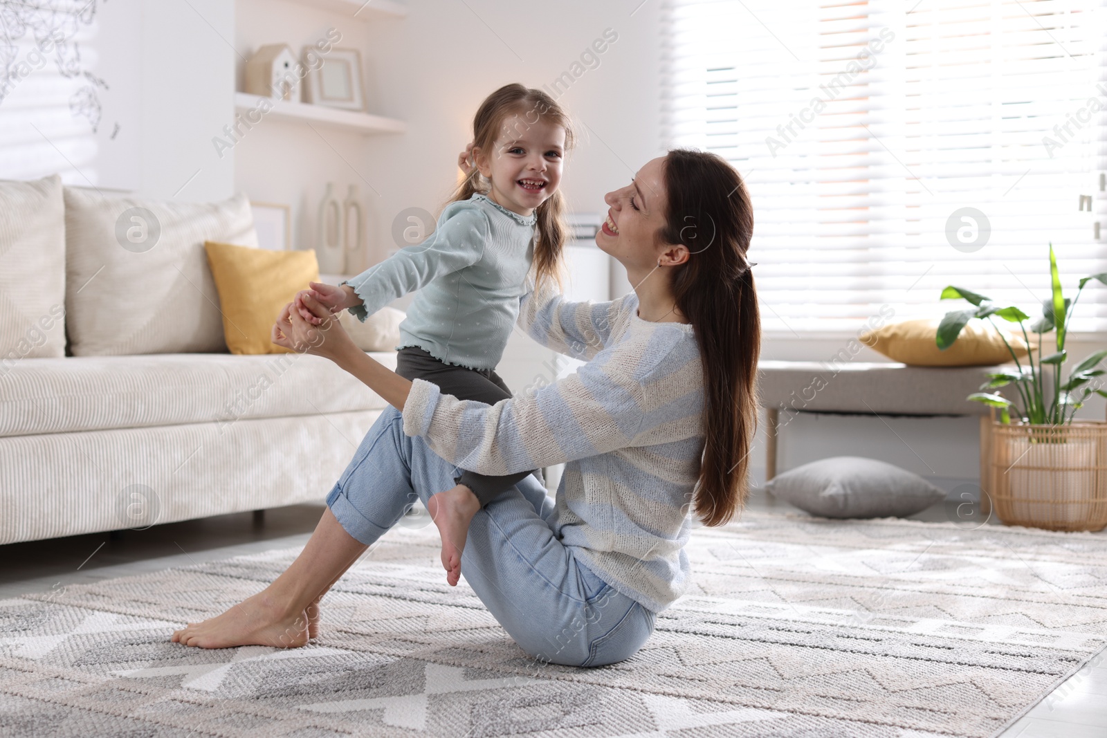 Photo of Happy mother with her cute little daughter on carpet at home