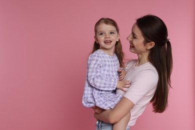 Photo of Happy mother with her cute little daughter on pink background, space for text