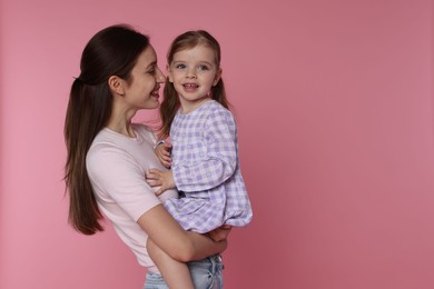 Photo of Happy mother with her cute little daughter on pink background, space for text