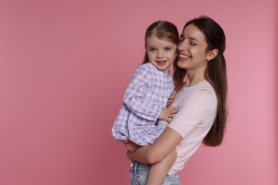 Photo of Happy mother with her cute little daughter on pink background, space for text