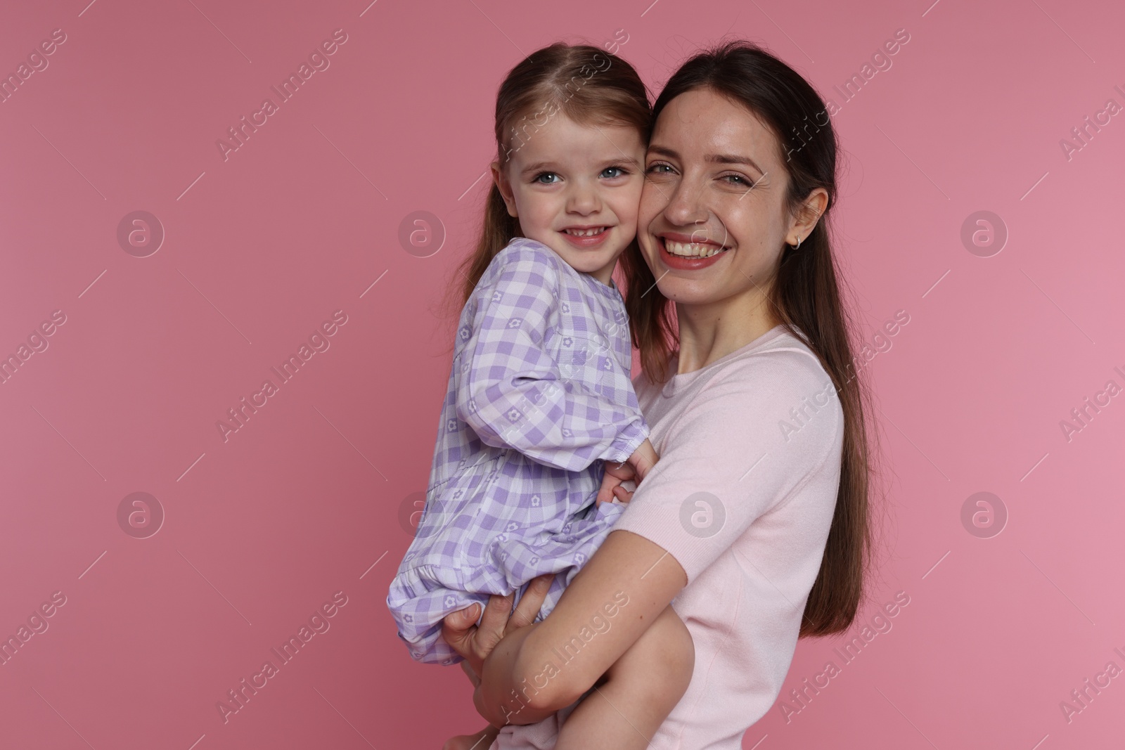 Photo of Portrait of happy mother with her cute little daughter on pink background