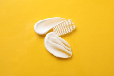 Photo of Smears of body cream on orange background, top view