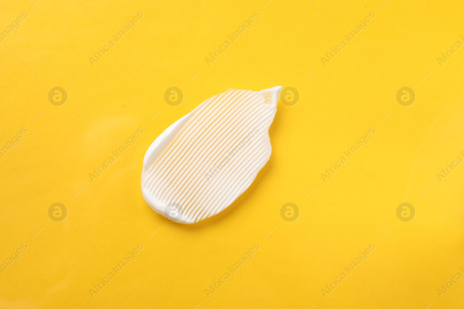 Photo of Smear of body cream on orange background, top view