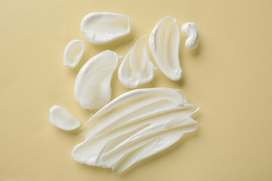 Photo of Smears of body cream on beige background, top view