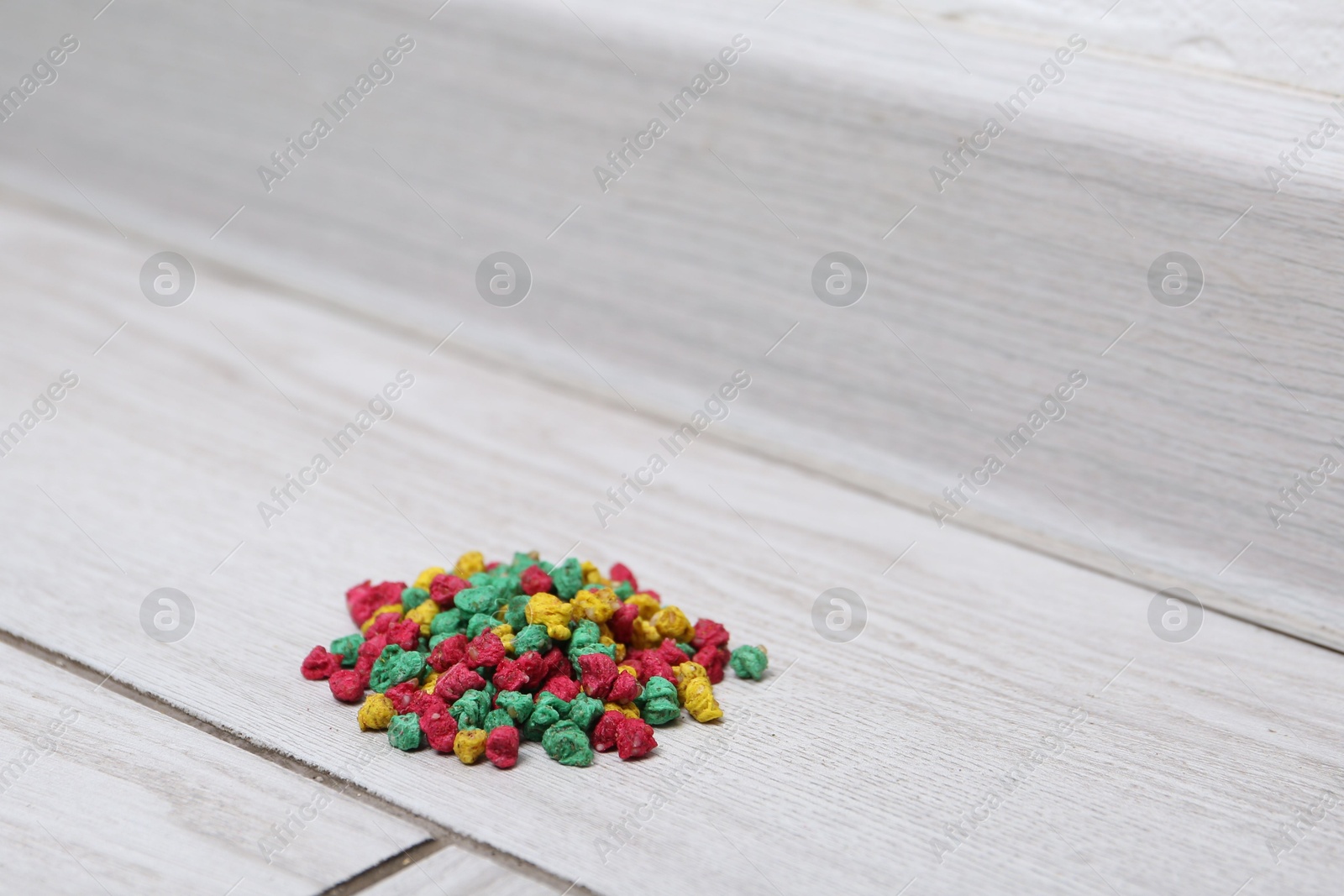 Photo of Pile of rat poison on floor indoors, closeup. Space for text