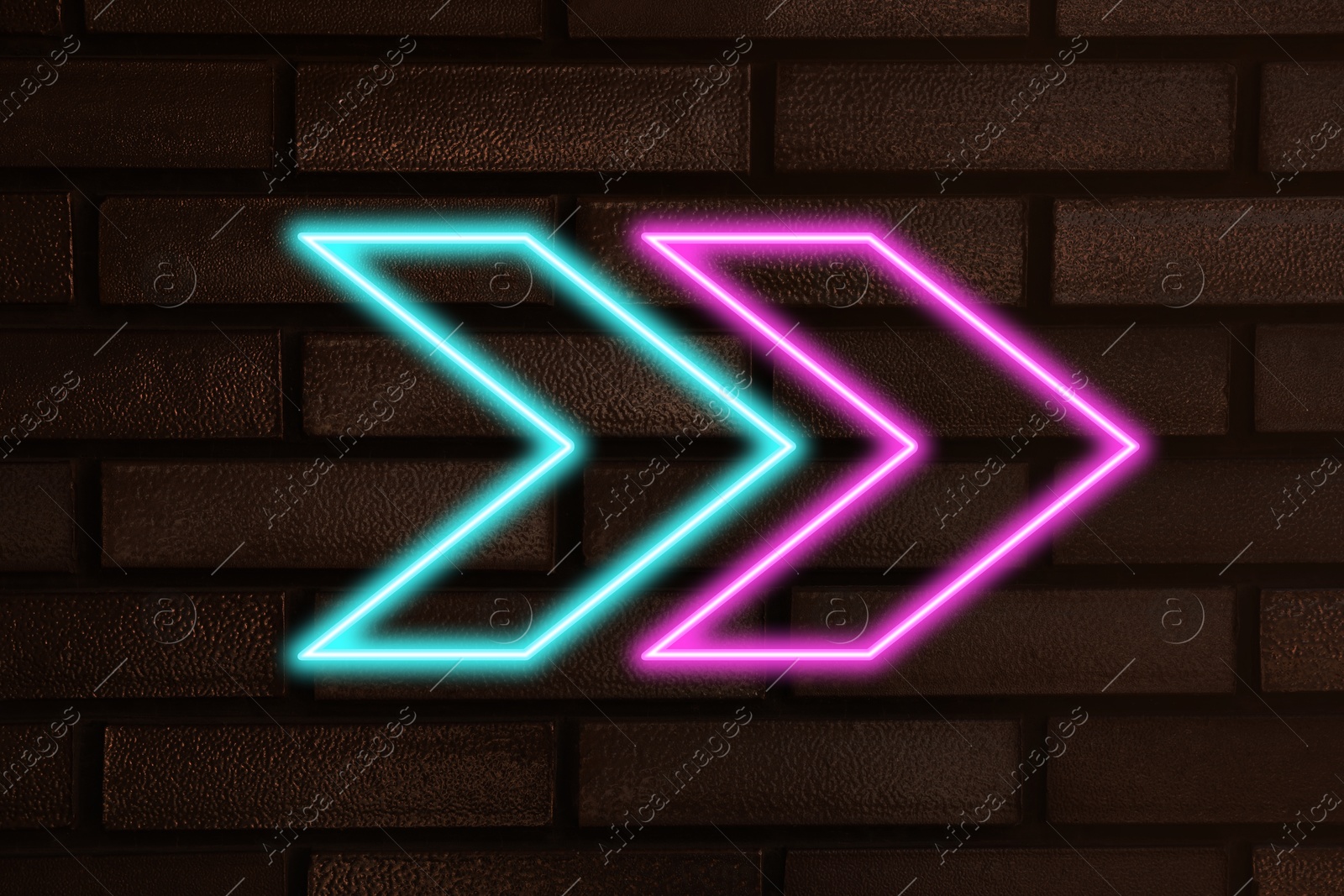 Image of Bright neon arrow-shaped pointer on brick wall