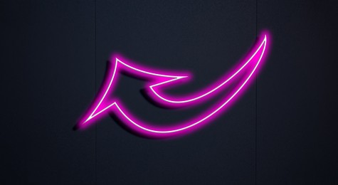 Image of Pink neon arrow-shaped pointer on black wall