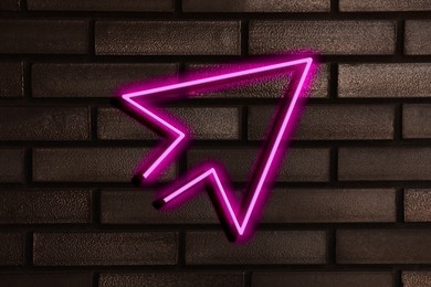 Image of Pink neon arrow-shaped pointer on brick wall