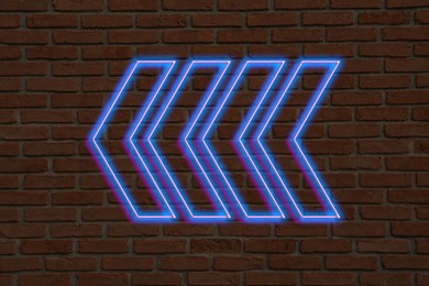 Image of Bright neon arrow-shaped pointer on brick wall